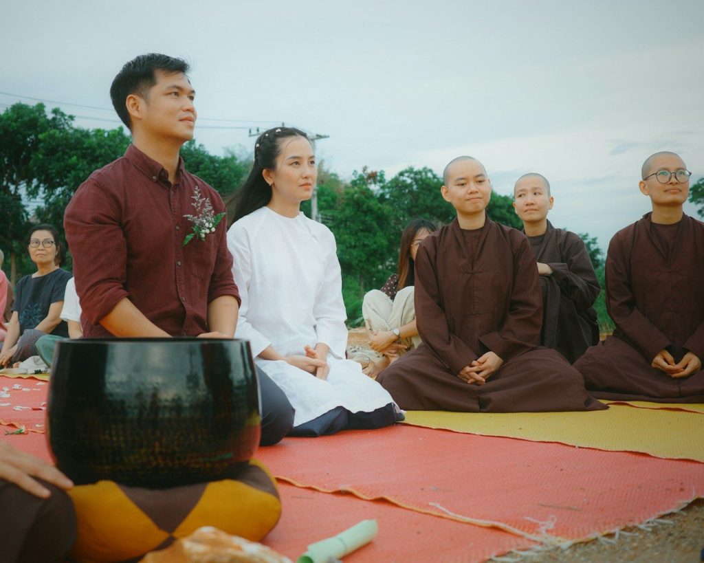 Attendees and buddhist monks sitting on mats outdoors
